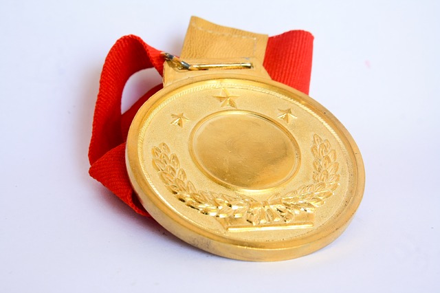 A gold medal with a red ribbon sits on a flat surface.